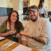 A photo of a couple toasting with drinks in a restaurant, celebrating an engagement.