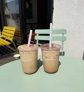 A simple, casual shot of two iced lattes on a table at Cuppello's, showcasing the branding on the cups.