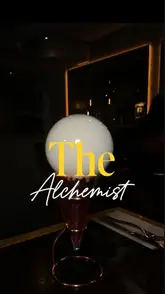A promotional reel for The Alchemist in Covent Garden, featuring a montage of theatrical cocktails being prepared with smoke effects, alongside close-ups of various food dishes like a steak sandwich, lobster mac and cheese, and fried seafood. The video uses fast-paced editing and text overlays to highlight the venue as a great spot for date nights and drinks.