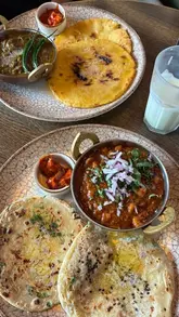 A creator visits Bombay Deli to review their new Desi brunch menu, showcasing the interior, the variety of traditional Indian breakfast dishes, and the lassi.