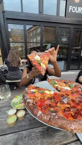 A review of Spring Street Pizza in London, featuring their 18-inch New York-style pizzas, specifically highlighting the nduja and stracciatella option, confit garlic dipping sauce, and vanilla soft serve dessert.