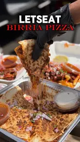 A short, high-quality food showcase featuring a birria pizza being pulled apart and dipped into consommé, followed by a shot of the 'Let's Eat' food truck.
