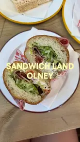 A personal review of Sandwich Land in Olney, where the creator visits the newly revamped shop to try their sandwiches and a sweet treat, highlighting the quality of ingredients and the welcoming atmosphere.
