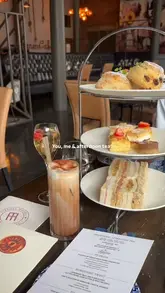 A montage showcasing an afternoon tea service at the Titanic Hotel in Liverpool, featuring close-ups of sandwiches, scones, cakes, and tea, alongside shots of the venue's interior and dockside views.
