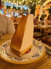 A high-quality, eye-level shot of a generous slice of lemon meringue pie, showcasing the impressive height of the meringue and the texture of the crust. The background is softly blurred, maintaining focus on the dessert.