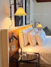 A clean, aesthetically pleasing shot of a hotel bedroom interior, focusing on the headboard and bedside table setup to evoke a sense of luxury and relaxation.