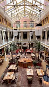 A visually appealing, polished reel showcasing a picnic-style afternoon tea service at The Nomad Hotel in London, featuring close-ups of sandwiches, scones, and pastries in a beautiful atrium setting.