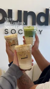 A vlog-style video featuring a visit to Ground Up Society cafe and Ambala on Green Street, East London. The creators show off their iced lattes and matcha drinks, as well as picking up vegetable samosas.