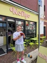 A casual, candid snapshot of a child holding an acai bowl outside the Kefiyo cafe, capturing a moment from a day out.