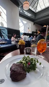 A montage video showcasing a meal at Hawksmoor, featuring various dishes like steak, chips, salads, and desserts, alongside cocktails and wine. The video highlights the restaurant's interior and the dining experience.