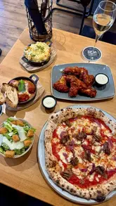 A short, visually appealing montage showcasing the exterior and various dishes at Base Pizzeria & Bar, including pizza, meatballs, mac and cheese, and chicken wings.