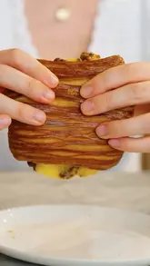 A close-up, first-person perspective shot of a laminated pastry being held by a person, promoting a new brunch menu at a venue in St John's Wood.