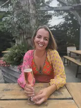 A portrait of a woman enjoying a glass of sparkling wine at an outdoor pub table, promoting a stay at a Norfolk pub.