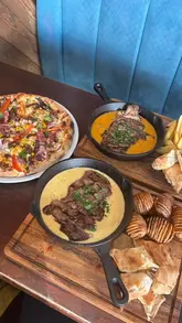 A montage showcasing various dishes including steaks, pizza, nachos, and mocktails at Salt & Crust restaurant.