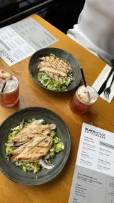 The creator visits Blackhouse in Leeds for a bottomless brunch, highlighting the variety of cocktails and the quality of the food menu, which includes small plates and mains. The video features shots of the venue, the menu, various cocktails, and dishes like anchovies and caesar salad.