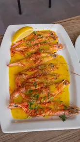 A food review video featuring a creator visiting 'Shrimp & Co' in Liverpool. The video highlights several dishes including barbecue ribs, garlic butter shrimp, a soft shell crab burger, a seafood boil platter, and a chocolate fondant dessert. The creator provides commentary on the taste and texture of the food throughout the video.