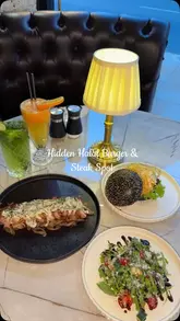 A short, engaging video showcasing new menu items at Gourmet Burger Club, including a charcoal bun burger, steak, onion rings, and a cookie gelato burger. The creator highlights the food and the venue's atmosphere.