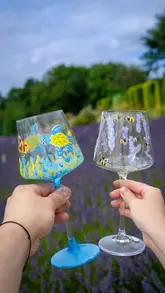A couple enjoys a creative date night painting wine glasses while sitting in a lavender field. The video highlights the 'Pott'd' craft kit and the relaxing, scenic atmosphere of the location.