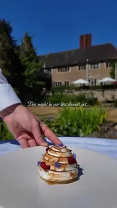 A short, slow-motion video showcasing a Cherry Bakewell Baked Alaska dessert being served and cut open in an outdoor garden setting.