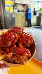 A short video showcasing a Korean food stall in a food hall where a robotic arm prepares the food. The video features shots of the robot in action, the menu, and the final dish of Korean fried chicken and fries.