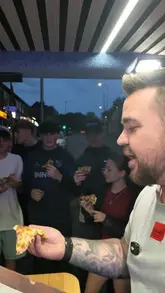 A creator reviews a pizza and a mixed kebab from PK's Pizzeria in Padiham, accompanied by a group of young people. The video features the creator's honest feedback on the food quality and value, presented in a casual, vlog-style format.