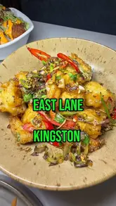 A creator visits East Lane in Kingston, a new Pan-Asian restaurant, showcasing a variety of dishes including bao buns, salt and pepper prawns, chicken karaage, chilli beef, dumplings, lamb chops, and Thai green curry, alongside cocktails.