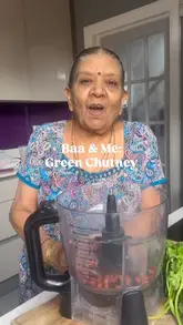 A home cooking tutorial featuring a grandmother and granddaughter preparing a green chutney recipe in a home kitchen.