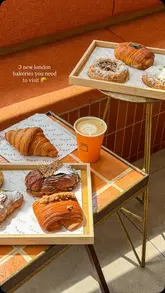 A high-quality, overhead flat-lay shot showcasing a variety of pastries and a coffee, likely from a bakery. The lighting is soft and natural, highlighting the textures of the baked goods.