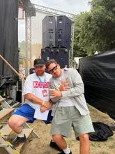 A casual photo of two men posing in front of large speakers at an outdoor festival or event, likely in Dublin.
