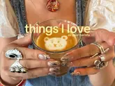 A close-up, aesthetically pleasing shot of a barista holding a glass of coffee with bear-shaped latte art. The image highlights the craft of coffee making while incorporating the creator's personal style through detailed nail art and rings.