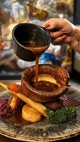 A montage video showcasing a Sunday roast experience at God's Kitchen in Swansea, featuring close-ups of various meats, sides, and gravy pouring.