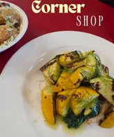 A top-down shot of a meal at Corner Shop in Glasgow, featuring grilled courgettes with cauliflower puree and a side of roast potatoes.