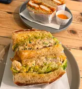 A close-up, appetizing shot of two sandwiches served on plates on a wooden table, showcasing the menu at a new sandwich spot in Exeter.