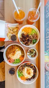 A montage of various Japanese-inspired comfort food dishes, including omurice, katsu curry, dumplings, and takoyaki, filmed in a casual dining setting.