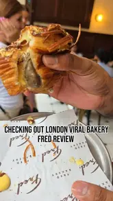 A creator visits Fred Bakery in London to review their viral pastries. The video features a tour of the bakery's interior, a look at the display case, and a taste test of several items including a croissant, pistachio bun, cinnamon bun, and a tiramisu croissant, with honest feedback on each.