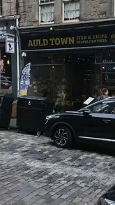 A review-style video featuring two creators visiting Auld Town Fish & Chips in Edinburgh. The video includes shots of the exterior, interior, and several dishes including haggis bonbons, fish and chips, a burger, and a steak pie.