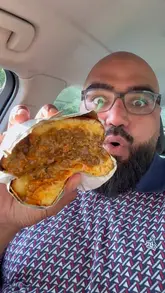 A candid, vlog-style review of a takeaway venue called The Scran Guys in Manchester. The creator samples several items including a parmo, a Philly cheesesteak toastie, loaded fries, shrimp, and a dessert, providing honest feedback on each while eating in his car.