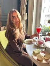 A high-quality lifestyle shot featuring a woman enjoying an afternoon tea service at a hotel, showcasing the elegant atmosphere and the food and drink experience.