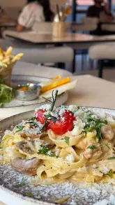 A short, aesthetic montage showcasing the interior decor and various food items at Monaco Cafe, including drinks, a burger, pasta, and a decadent French toast dessert.