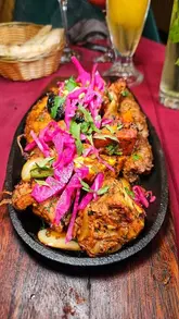 A food review video featuring a variety of dishes from an Indian restaurant, including a tandoori mixed grill, lamb chops, samosas, cocktails, and a hariyali lamb curry. The creator provides a voiceover review of the food and atmosphere at Saffron Soho.