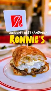A creator reviews a New York-style sandwich spot in London, showcasing various dishes including a French dip, Reuben, fried chicken sandwich, and desserts. The video features the creator's enthusiastic commentary and close-up shots of the food.