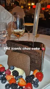 A close-up, slow-motion shot of a large, multi-layered chocolate cake being sliced and served at Smith & Wollensky.