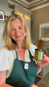 A home cooking tutorial demonstrating how to make fresh pesto using a food processor, featuring basil, cashews, parmesan, garlic, and olive oil.