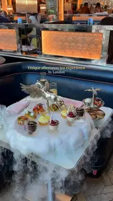 A short, polished video showcasing the Pegasus afternoon tea experience at Brasserie of Light in London. The footage features close-ups of the tea stand, including savoury bites, scones, and miniature desserts, enhanced by a dry ice effect, alongside shots of the restaurant's opulent interior and iconic Pegasus sculpture.