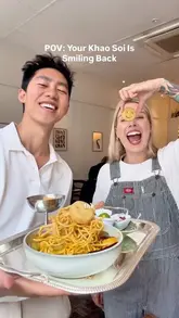 A couple showcases a playful 'Khao Soi' dish featuring smiley-face potato snacks at a restaurant called Plants of Roslin, demonstrating the assembly of the meal.