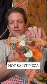 A creator reviews Hot Saint Pizza, located within The Old Queens Head in Angel, London. The video features a taste test of different pizzas, including the spicy Hawaiian and meatball ricotta, along with sides like hot pickles and garlic bread. The creator provides commentary on the quality of the pizza bases, the toppings, and the available dips, while also giving a glimpse of the pub's interior and exterior.