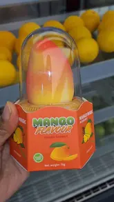 A short, handheld video showcasing a mango-shaped frozen dessert, featuring close-up shots of the packaging and the product itself after a bite is taken.