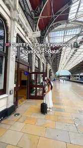 A travel vlog documenting a First Class train journey from London to Bath via GWR, showcasing the lounge amenities, comfortable seating, and complimentary refreshments.