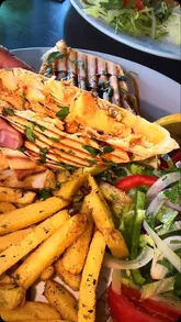 A promotional video for The Olive Kitchen in Oxford, showcasing the restaurant's exterior, menu, and a selection of Lebanese dishes including chicken shawarma, grilled seabass, and spicy batata.