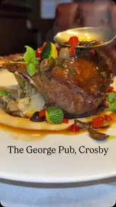 A review of The George Pub in Crosby, featuring a couple trying various dishes including scallops, chicken satay, a Scotch egg, a rack of lamb, and a chocolate tart.